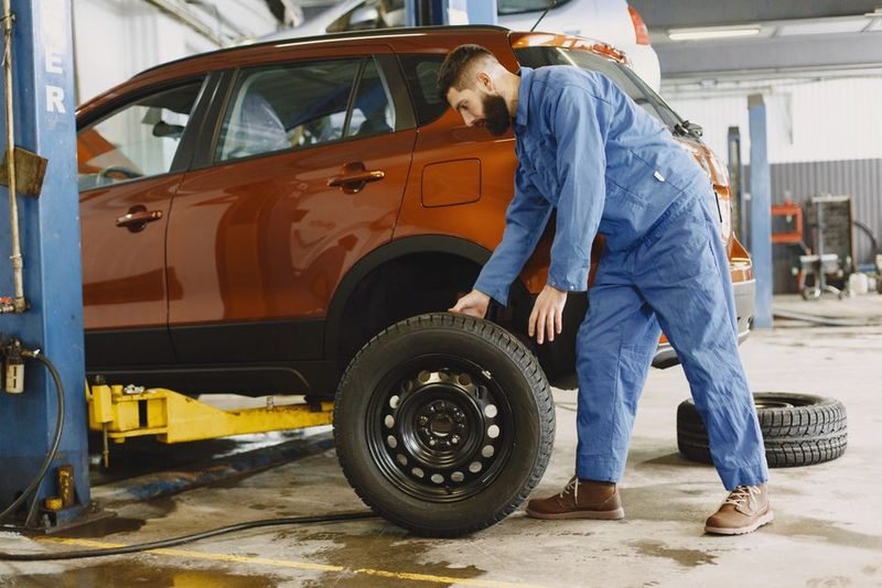 Mechanic changing a tire on a vehicle up on the hoist.